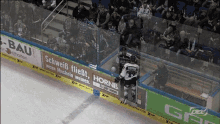 a hockey player stands on the ice in front of a banner that says hornb on it