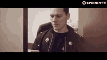 a man in a black jacket is looking at a cell phone ..