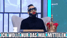 a man with a beard and sunglasses is sitting in a chair with a crown on the table .