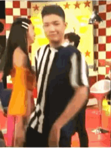 a man and a woman are dancing in a room with a checkered wall .