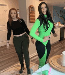 a woman in a green costume is standing next to another woman in a black top