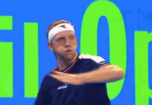 a man wearing a headband and a black shirt is standing in front of a green and blue background .
