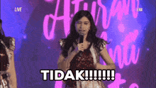 a girl is holding a microphone and says tidak
