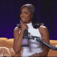 a woman is sitting in front of a microphone with her hand on her chin