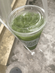 a plastic cup with a green liquid in it and the word tea on it