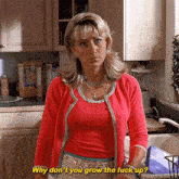 a woman in a red cardigan is standing in a kitchen and says why don 't you grow the fuck up