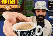 a man is holding a coffee cup in front of a screen that says spins