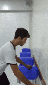 a man cleaning a row of blue chairs in a classroom