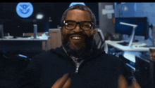 a man with glasses and a beard is smiling in front of a sign that says u.s. department of homeland security