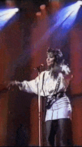 a woman sings into a microphone on a stage