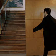 a man in a black coat is walking down stairs