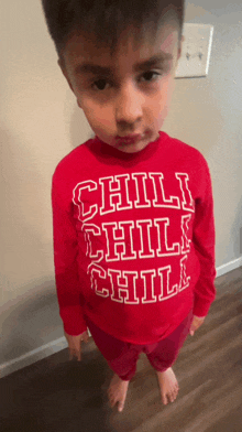 a young boy wearing a red shirt that says chili chill