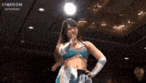 a woman in a wrestling outfit is pointing at the camera with the word stardom behind her