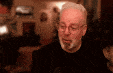 a man with glasses and a beard is looking at something
