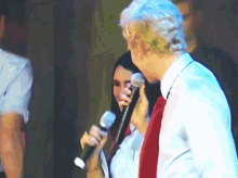 a man holding a microphone next to a woman on a stage