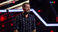 a man in a black and white shirt stands on a stage with the words la voz argentina on the bottom