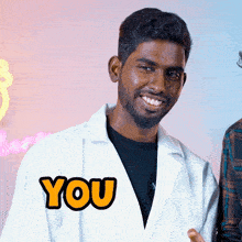 a man wearing a white lab coat has the word you on his jacket