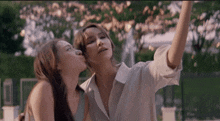 a woman kisses another woman on the cheek while they take a selfie