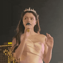 a woman wearing a tiara holds a microphone