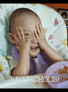 a baby in a high chair covering his eyes with his hands and a plate of food behind him that says " recorcholis "