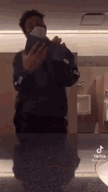 a man wearing a face mask is taking a picture of himself in a public restroom .