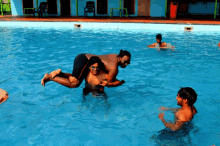 a man is carrying another man on his back in a pool