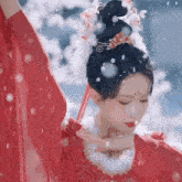 a woman in a red dress is dancing in the snow while wearing a crown .