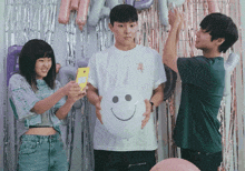 a man holding a smiley face balloon is surrounded by people