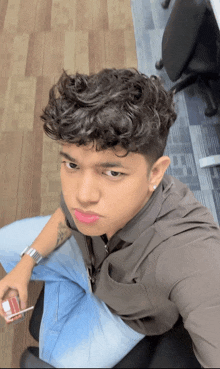 a young man with curly hair is taking a selfie with his phone