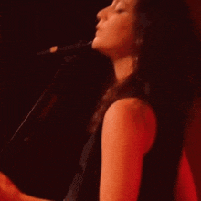a woman in a black dress is singing into a microphone .