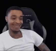 a man in a white shirt is sitting in a chair and smiling .