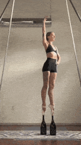 a woman wearing pointe shoes is balancing two bottles of champagne on her feet