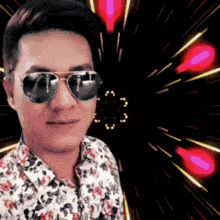 a man wearing sunglasses and a floral shirt is standing in front of a fireworks display