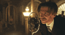 a man speaking into a microphone with the words by order of the peaky blinders behind him