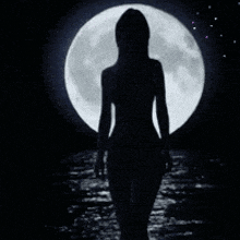 a woman stands in front of a full moon