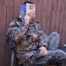 a man in a military uniform has a book on his face