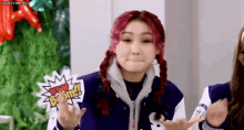 a woman with red hair is wearing a blue jacket and holding a sign that says boom .