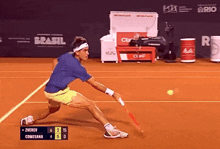 a tennis player in a blue shirt and yellow shorts is playing a game against comesana