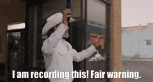 a man in a cowboy hat says " i am recording this "