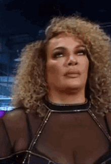a woman with curly hair is wearing a black top and making a funny face