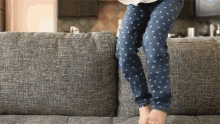 a person wearing blue polka dot pants is jumping on a couch
