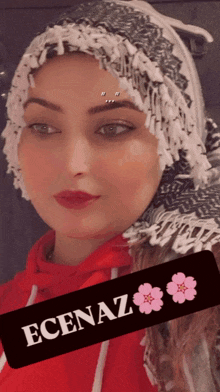 a woman wearing a scarf and a red hoodie has the name ecenaz on a black sticker
