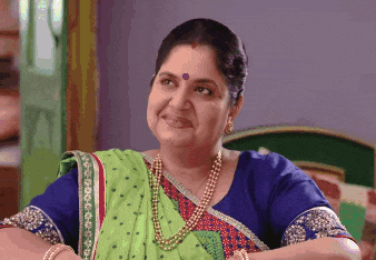 a woman in a green saree and blue top smiles