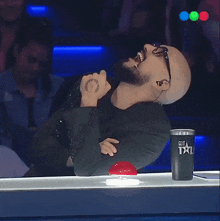 a bald man is singing into a microphone next to a cup that says got talent