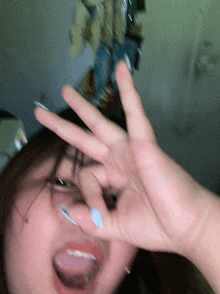a woman with blue nails is making a funny face with her hand