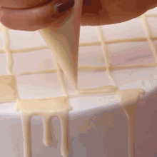 a person is frosting a white cake with a piping bag