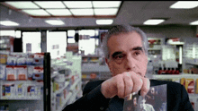 a man in a black suit is holding a picture of a man in a pharmacy