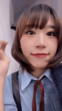 a close up of a girl wearing a blue shirt and a red tie