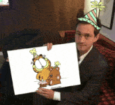 a man wearing a party hat is holding a garfield drawing