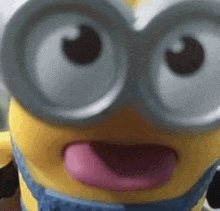 a close up of a toy minion with its tongue out and glasses on .